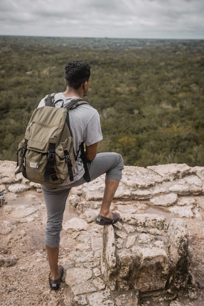 Ein Mann steht mit einem Rucksack auf einem Berg | Kofferworld Gutschein | rabattecoupons 
