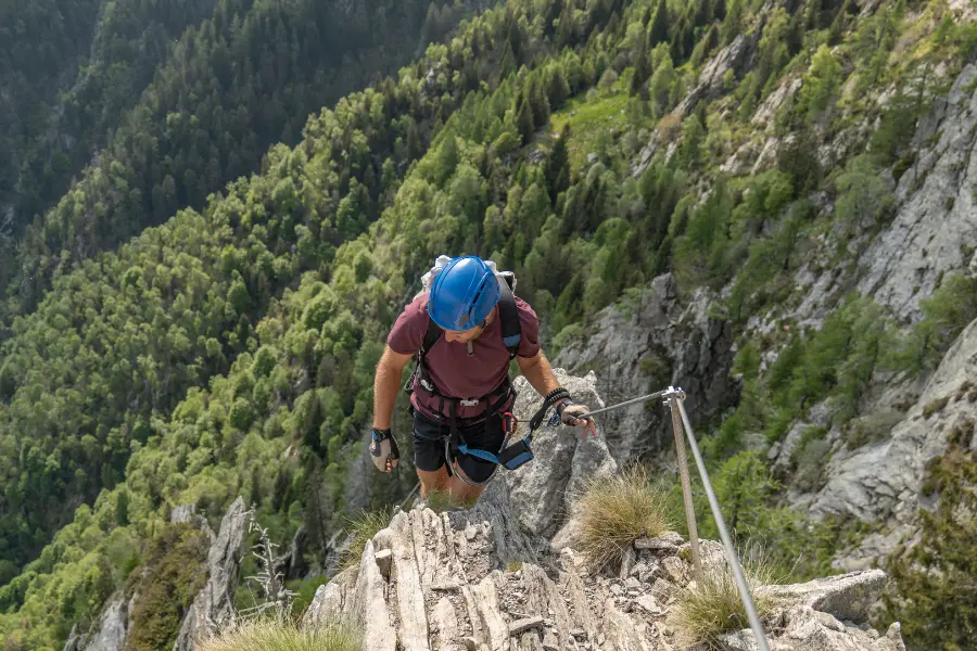 Kletterer mit Helm und Sicherung auf einem steilen Klettersteig in felsiger Berglandschaft
