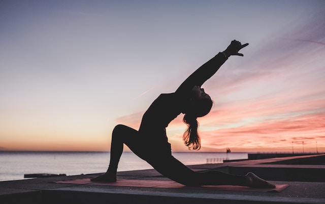 Eine Frau beim Yoga im Sonnenuntergang | rabatte coupons
