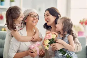 Familie schenkt einer älteren Frau Blumen und Geschenk zum Muttertag