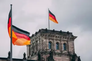 Deutsche Flaggen wehen vor dem Reichstagsgebäude in Berlin unter einem bewölkten Himmel.
