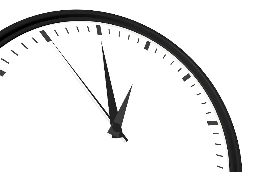 Close-up of a minimalist analog clock face with black hands and hour markers on a white background.