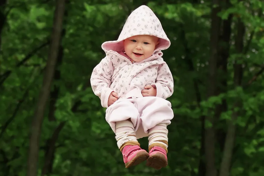 Lachendes Baby scheint vor grüner Waldkulisse in der Luft zu schweben.