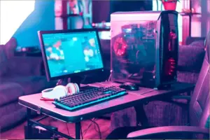 Gaming-PC mit Monitor, RGB-Tastatur, Maus und Headset auf einem Schreibtisch mit pink-blauer Beleuchtung