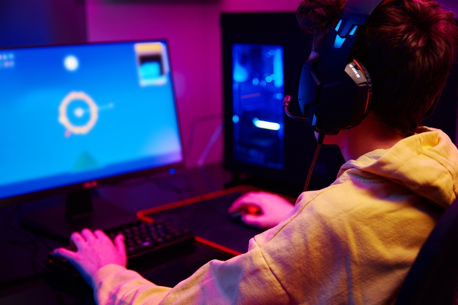 DSL-Anschluss wechseln: Wann, wie oft und welcher Tarif für wen 🛜 24 Junger Mann sitzt für einem PC und spielt bei pinken Licht in der Nacht.